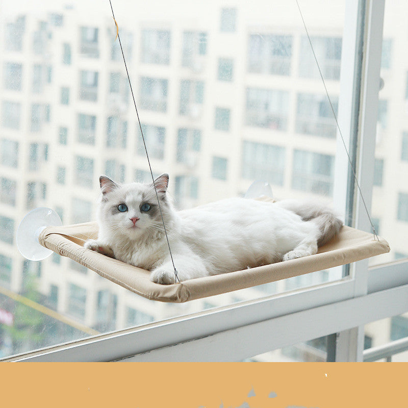 Khakikleurige raamhangmat met zuignappen aan een raam met een liggende kat