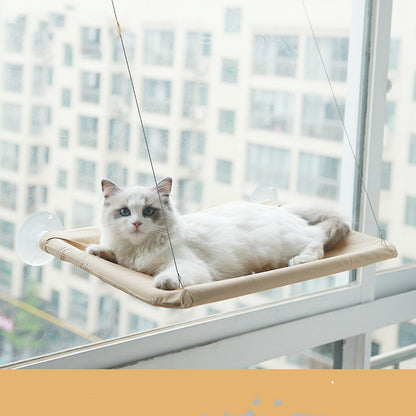 Khakikleurige raamhangmat met zuignappen aan een raam met een liggende kat