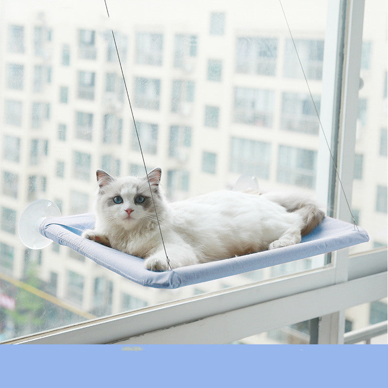Lichtblauwe raamhangmat met zuignappen aan het raam met een liggende kat