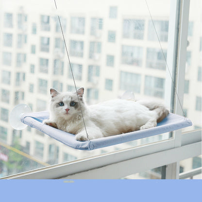 Lichtblauwe raamhangmat met zuignappen aan het raam met een liggende kat